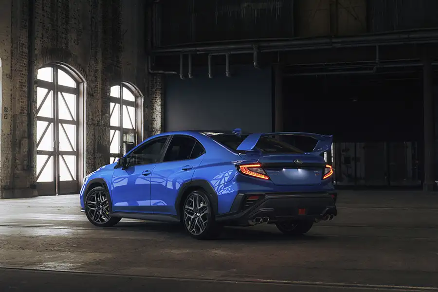 Đuôi xe Subaru WRX tS màu xanh lắp cánh lướt gió thể thao cỡ lớn trong xưởng cơ khí cũ.