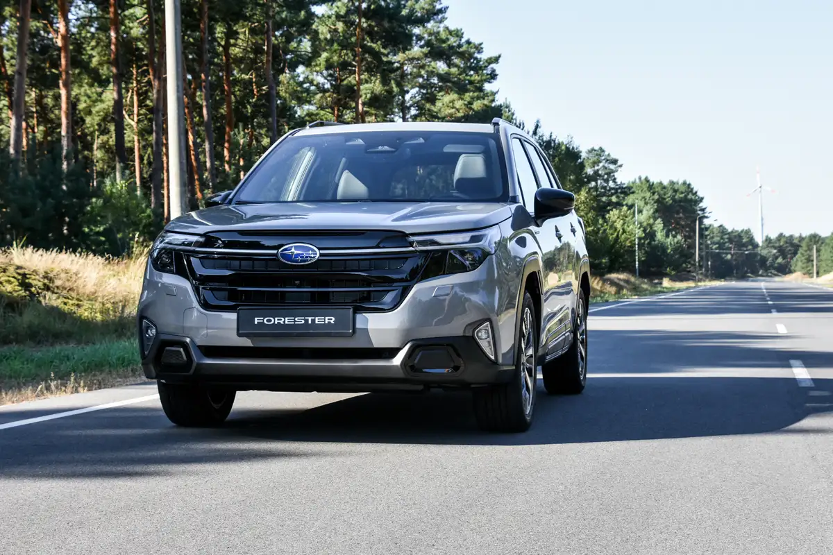Xe ô tô SUV Subaru Forester màu xám bạc đỗ trên đường nhựa với bối cảnh rừng cây xanh phía sau. Ảnh dùng so sánh Subaru Forester và Honda CR-V