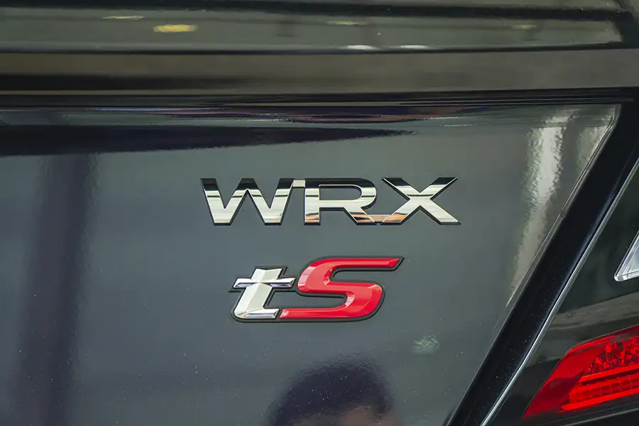 Cận cảnh logo chữ WRX mạ chrome và huy hiệu tS màu đỏ viền bạc trên nắp cốp sau xe ô tô Subaru.